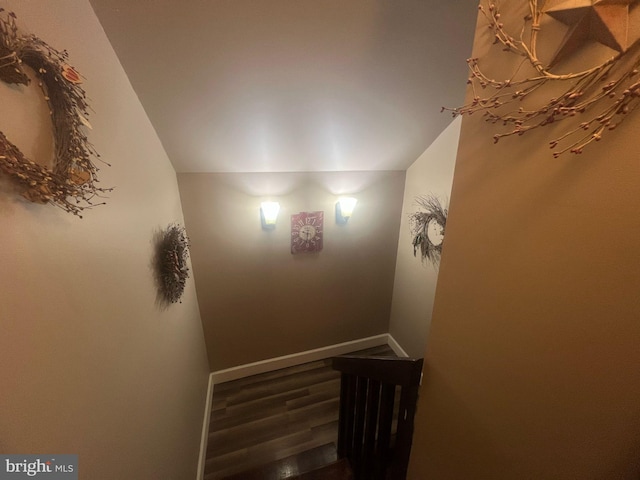 stairway featuring vaulted ceiling, wood finished floors, and baseboards