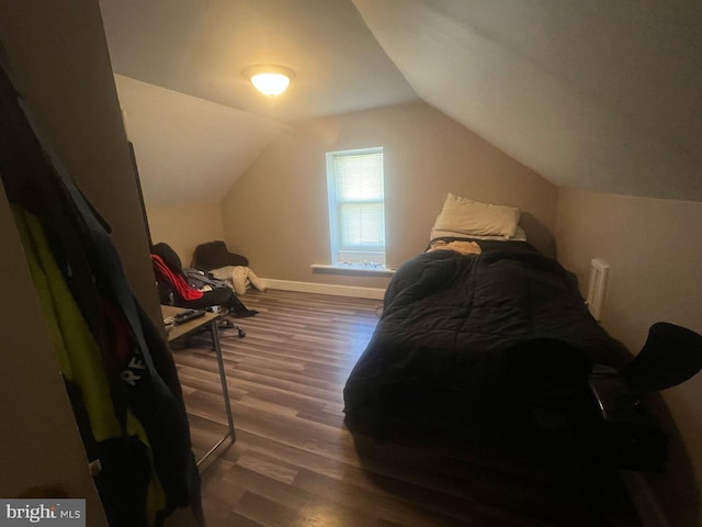 bedroom with vaulted ceiling, wood finished floors, and baseboards