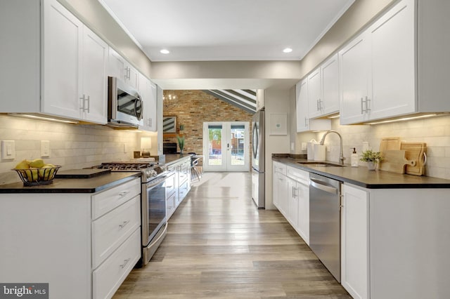 kitchen featuring dark countertops, stainless steel appliances, light wood-style floors, and a sink