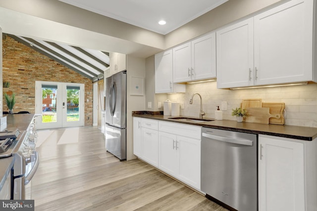 kitchen featuring dark countertops, stainless steel appliances, lofted ceiling with beams, and a sink