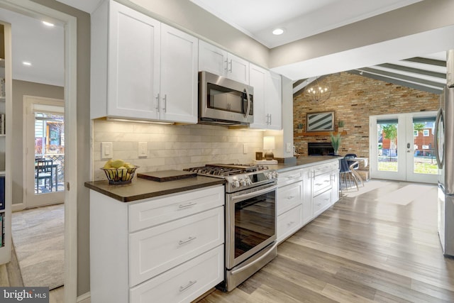 kitchen with tasteful backsplash, dark countertops, stainless steel appliances, light wood finished floors, and vaulted ceiling