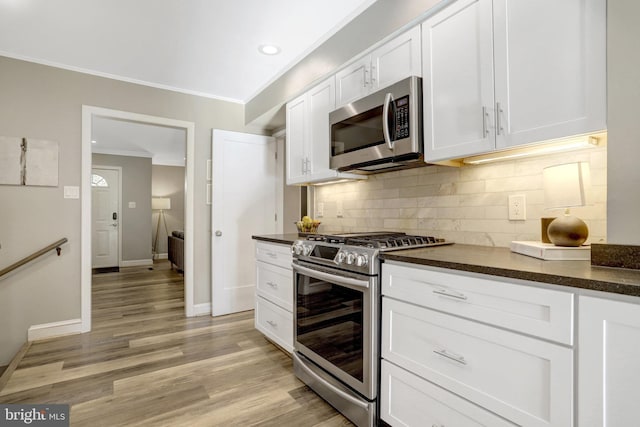 kitchen featuring dark countertops, white cabinets, appliances with stainless steel finishes, and ornamental molding