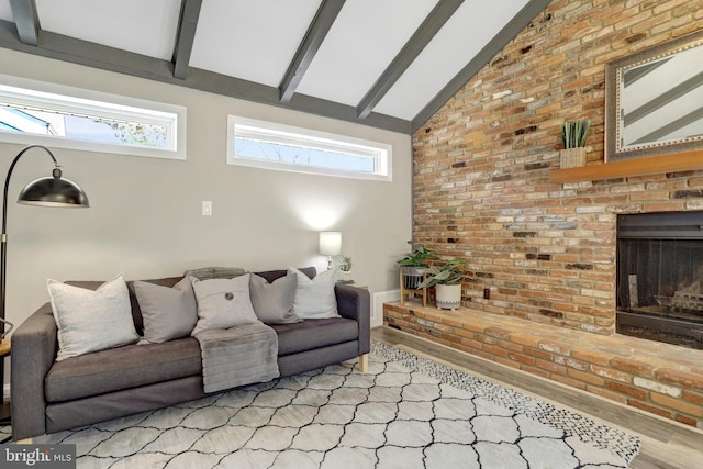 living room with plenty of natural light, beamed ceiling, a brick fireplace, and wood finished floors