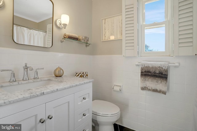 full bath with vanity, tile walls, toilet, and a wainscoted wall