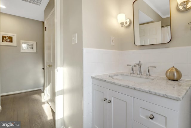 bathroom with wainscoting, tile walls, wood finished floors, and vanity