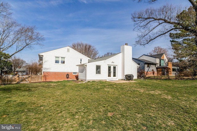 back of property featuring french doors, a yard, a chimney, and fence