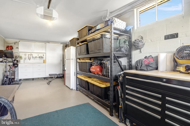 garage with concrete block wall, a garage door opener, and freestanding refrigerator