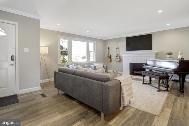 living room with a brick fireplace, light wood-type flooring, baseboards, and ornamental molding