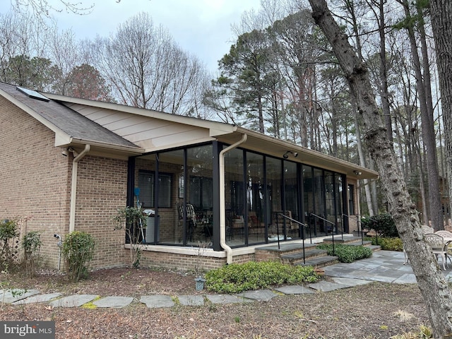 exterior space featuring a patio, brick siding, and a sunroom