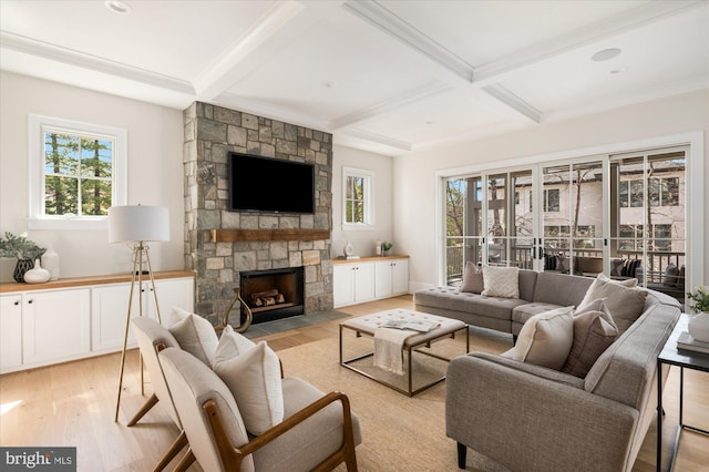 living room featuring a stone fireplace, coffered ceiling, light wood finished floors, and a healthy amount of sunlight