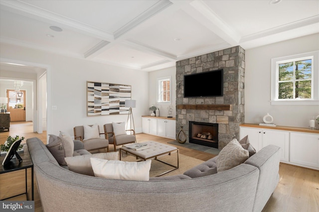 living area featuring a stone fireplace, beamed ceiling, coffered ceiling, and light wood-style floors