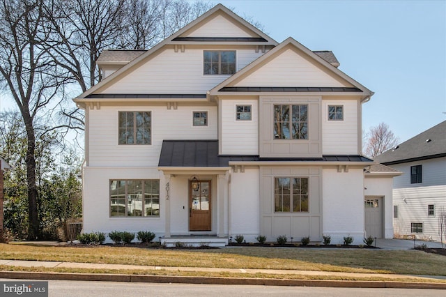 view of front of home featuring a standing seam roof, a front lawn, a garage, brick siding, and metal roof