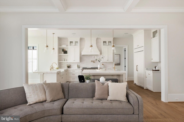 living room with beam ceiling, light wood-style flooring, crown molding, and baseboards