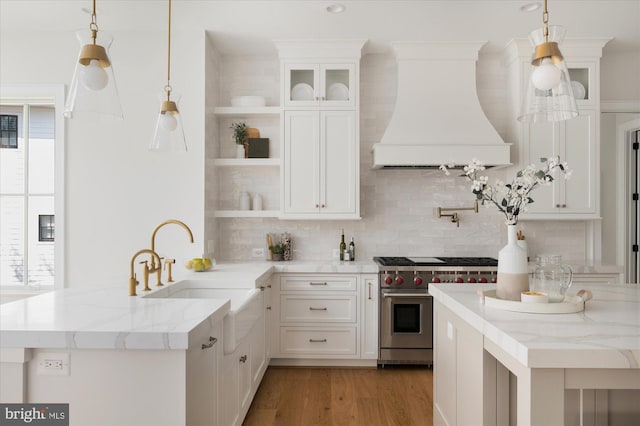 kitchen featuring luxury range, open shelves, premium range hood, a wealth of natural light, and a sink