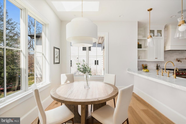 dining space featuring a skylight, light wood-style floors, and a wealth of natural light