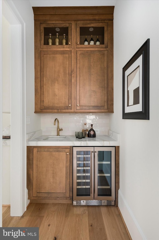 bar with a sink, backsplash, wine cooler, and light wood-style floors