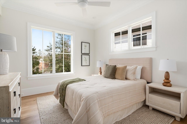 bedroom with crown molding, light wood-style flooring, baseboards, and ceiling fan