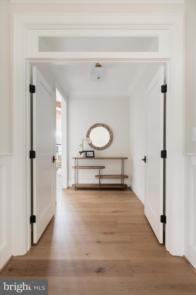 corridor featuring light wood-style flooring and ornamental molding