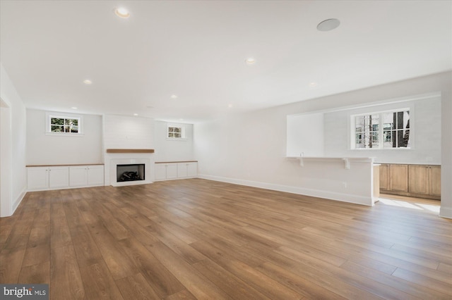 unfurnished living room featuring a fireplace, recessed lighting, light wood-style floors, and baseboards