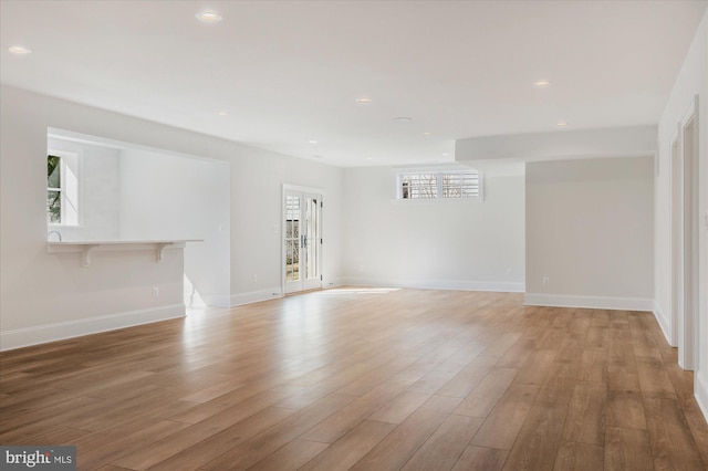 empty room featuring recessed lighting, baseboards, and light wood finished floors