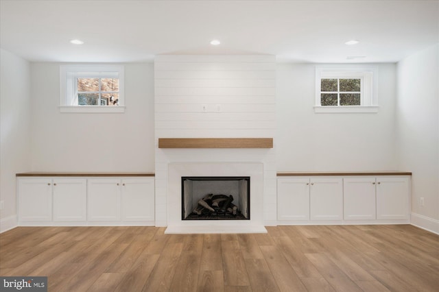 unfurnished living room featuring light wood finished floors, recessed lighting, a large fireplace, and baseboards