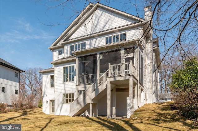 view of front of house with stairs, a front yard, a sunroom, and a chimney