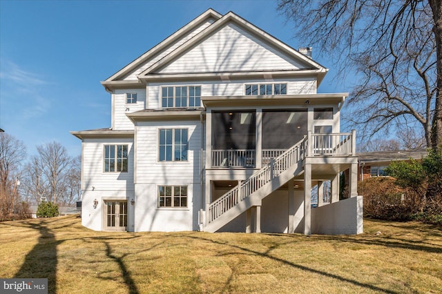 rear view of house featuring stairs, a yard, and a sunroom