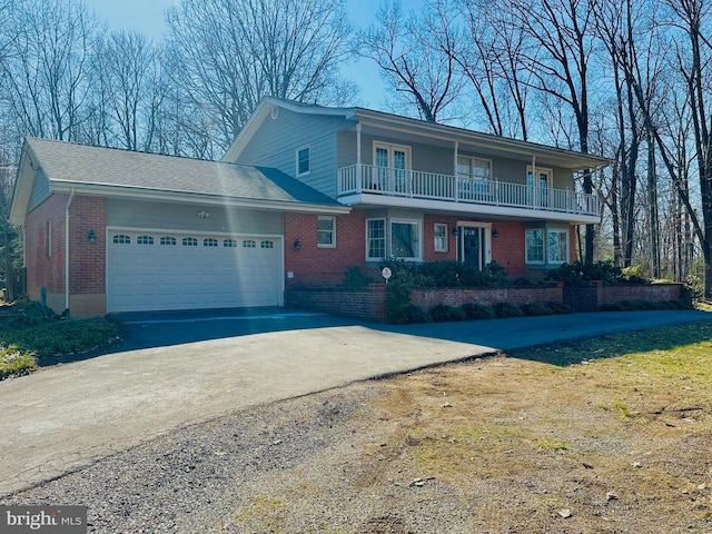 front of property featuring a garage, driveway, a balcony, and brick siding