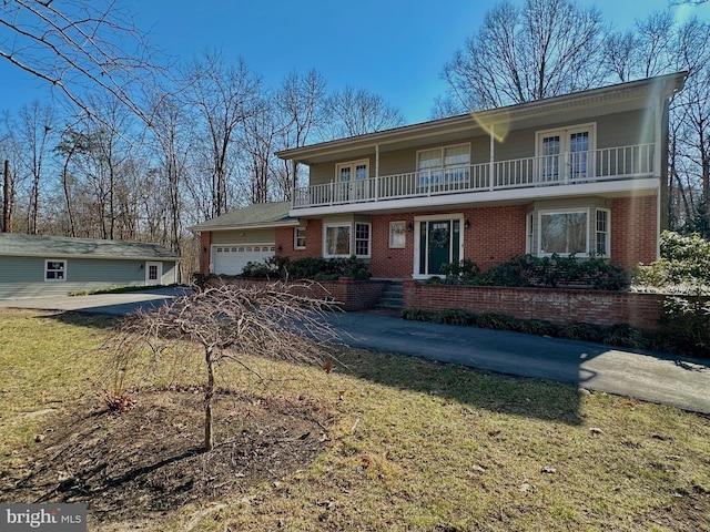 view of front property featuring brick siding, driveway, an attached garage, and a balcony