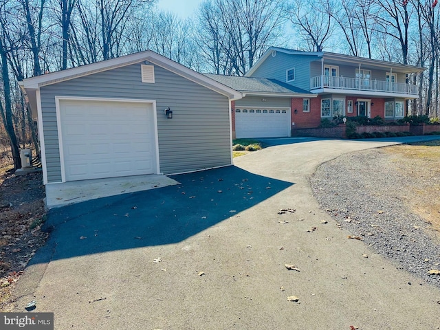 view of front facade featuring aphalt driveway, a garage, brick siding, and a balcony