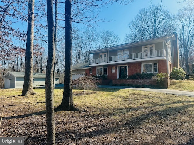 view of front of house featuring a front lawn, a balcony, a garage, and brick siding