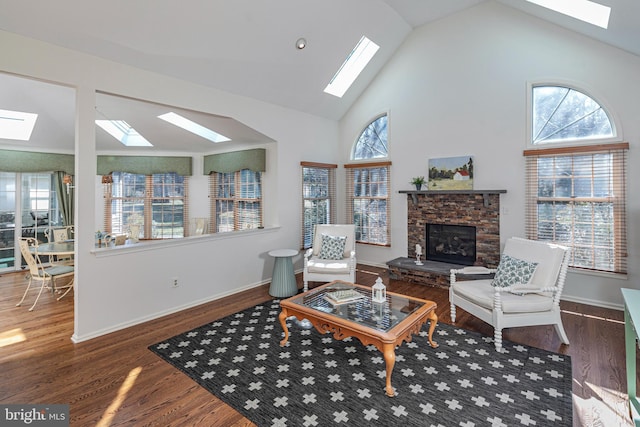 living area featuring a stone fireplace, a healthy amount of sunlight, and wood finished floors