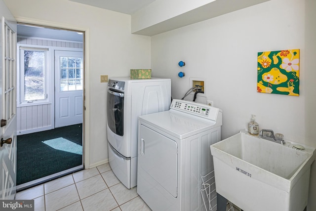 laundry area with light tile patterned floors, a sink, laundry area, and separate washer and dryer