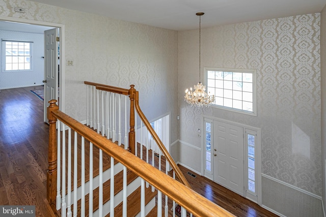 foyer with a chandelier, visible vents, wood finished floors, and wallpapered walls