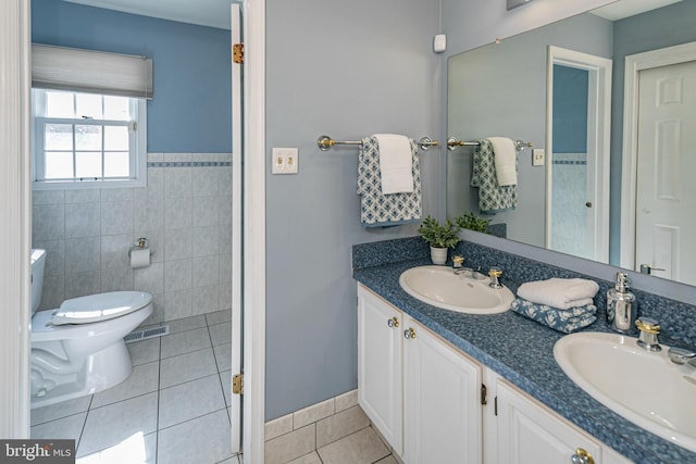 full bathroom featuring tile patterned flooring, toilet, tile walls, and a sink