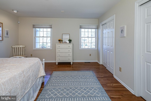 bedroom featuring baseboards, multiple closets, and dark wood-style flooring