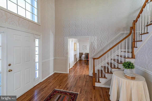 entryway with stairway, wood finished floors, and wallpapered walls