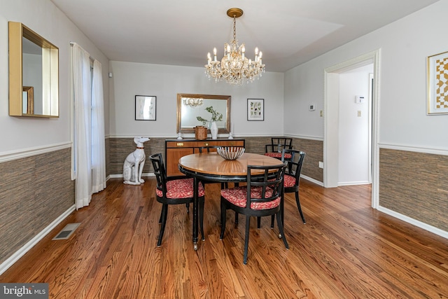 dining area featuring wood finished floors, visible vents, a chandelier, and wainscoting