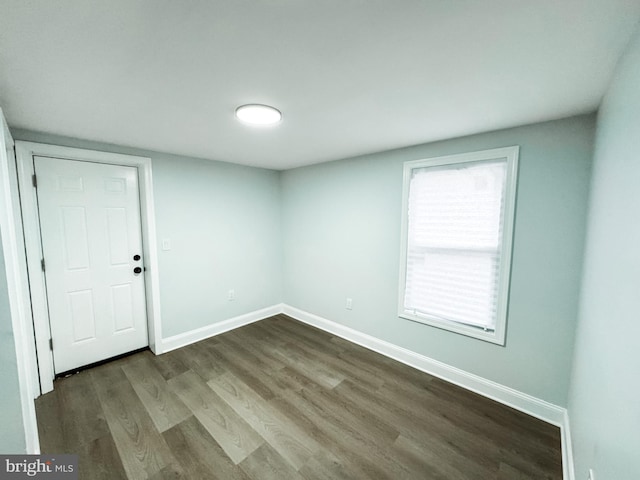 unfurnished room featuring baseboards and dark wood-style flooring