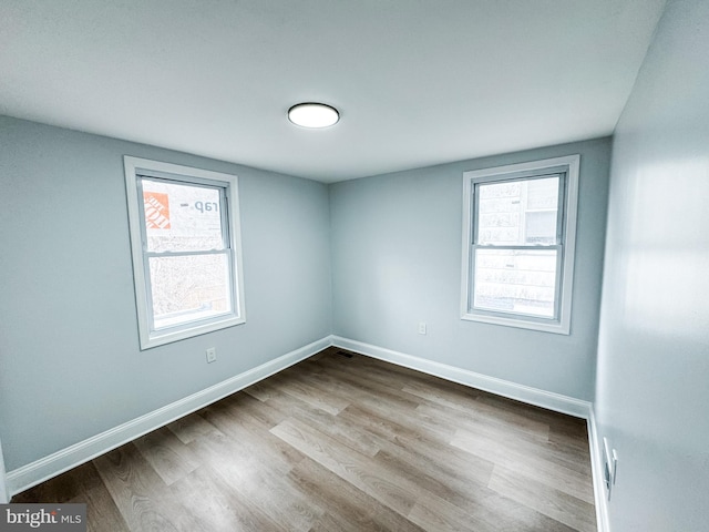 unfurnished room with plenty of natural light, baseboards, and wood finished floors