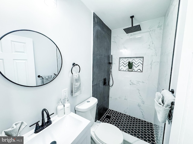 bathroom with toilet, tiled shower, and a sink