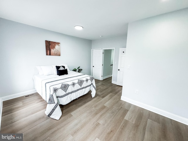 bedroom featuring visible vents, baseboards, and wood finished floors