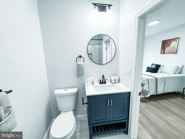 bathroom featuring connected bathroom, baseboards, toilet, wood finished floors, and vanity