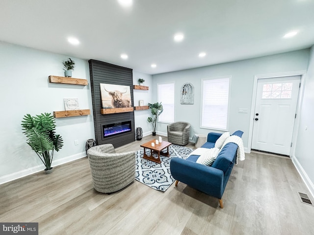 living area featuring visible vents, wood finished floors, recessed lighting, a large fireplace, and baseboards