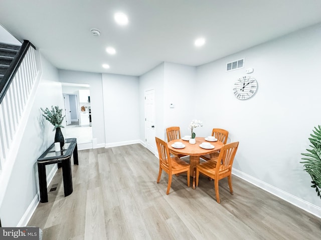 dining space with visible vents, stairway, baseboards, and wood finished floors