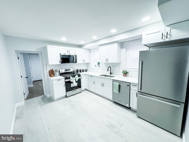 kitchen with white cabinets, stainless steel appliances, light countertops, and a sink