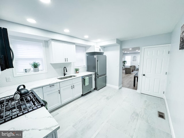 kitchen featuring visible vents, light stone countertops, white cabinets, stainless steel appliances, and a sink