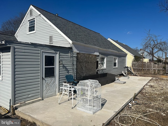 back of property with a patio area, fence, and a shingled roof