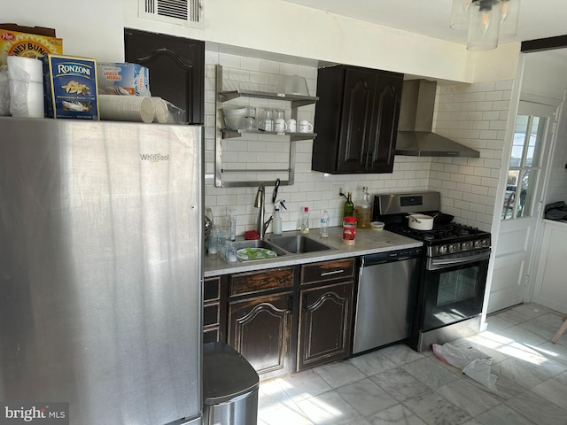 kitchen featuring visible vents, light countertops, stainless steel appliances, wall chimney exhaust hood, and a sink