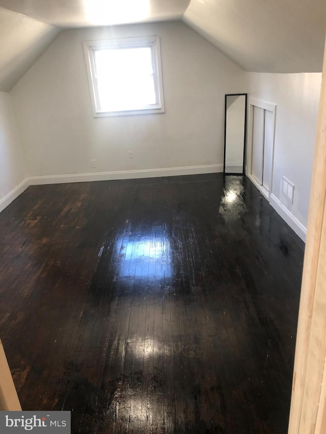 additional living space with vaulted ceiling, baseboards, and wood-type flooring